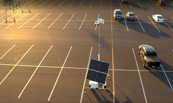 An LVT mobile security unit equipped with solar panels and elevated cameras in a parking lot. 