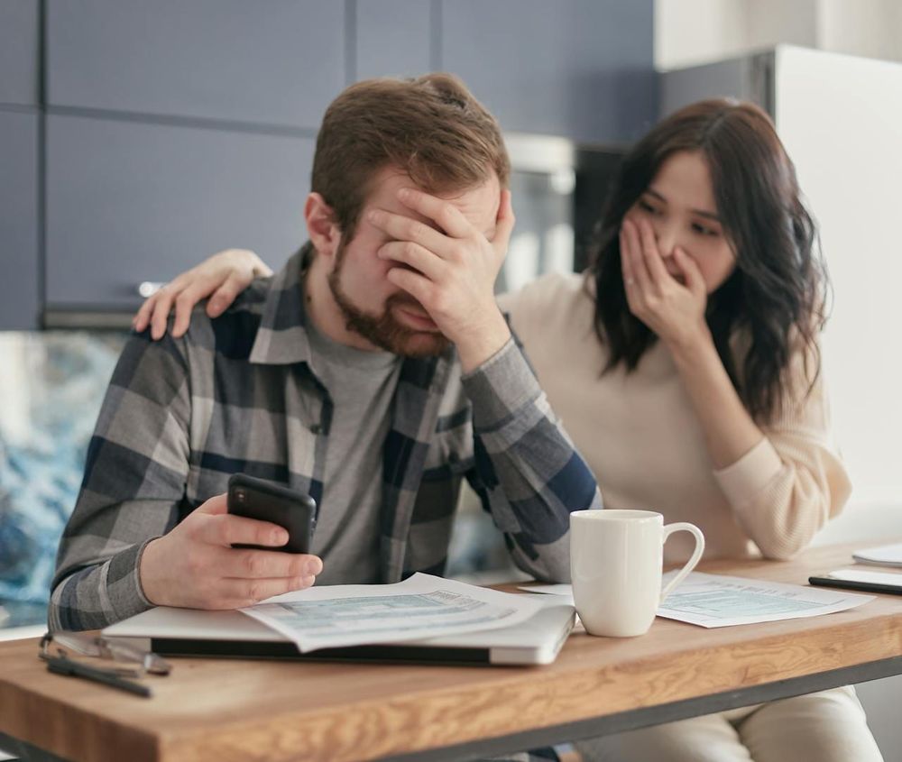 Couple consultant un relevé bancaire et faisant facepalm.