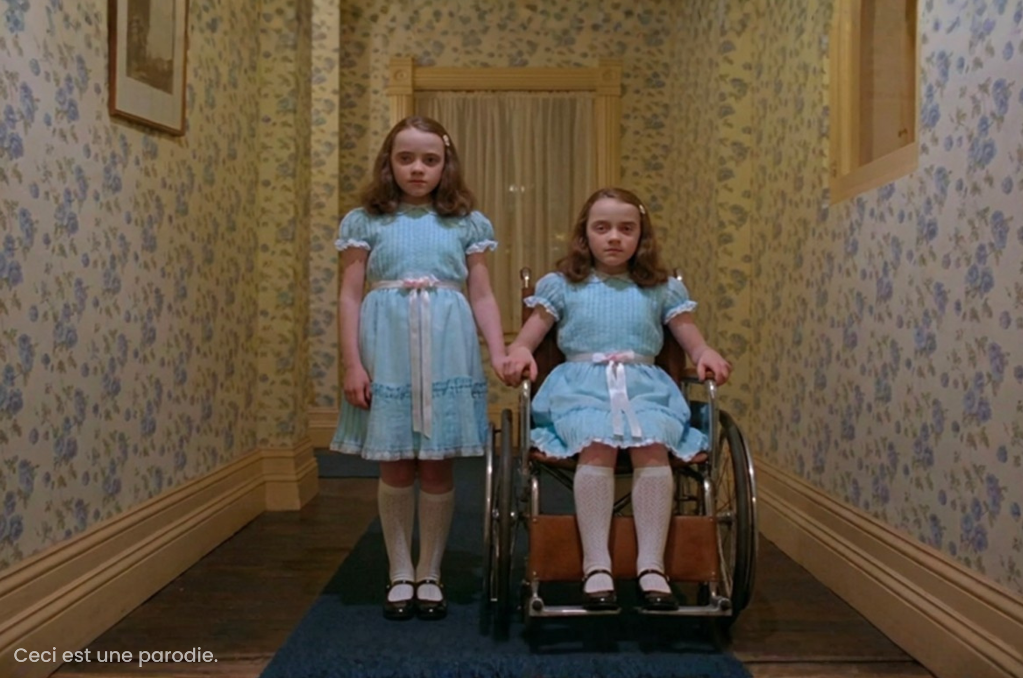 Deux fillettes, jumelles, aux visages fermés, vêtues de robes bleues identiques, se tiennent par la main dans un couloir étroit aux murs tapissés de fleurs, l’une debout et l’autre assise dans un fauteuil roulant manuel. En bas à gauche de l’image, une petite mention en texte blanc indique « Ceci est une parodie. »