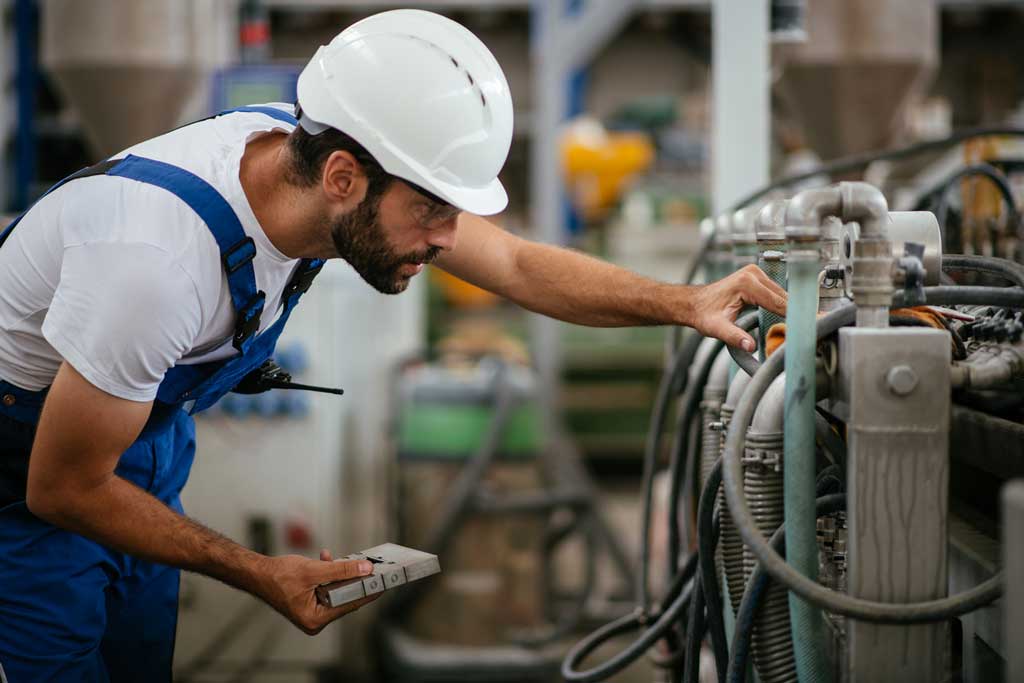 hydraulic fluid selection: worker looking at machinery with fluid pipes