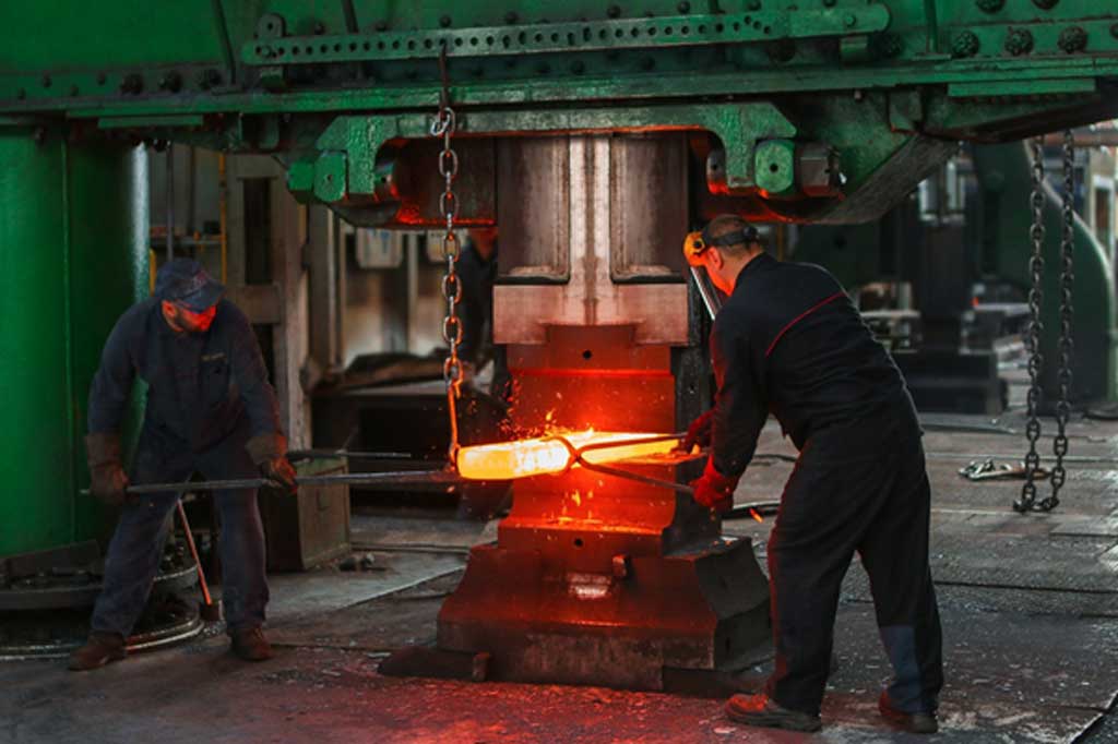Strain hardening: Two metal workers can be seen here forming metal after is has been heated