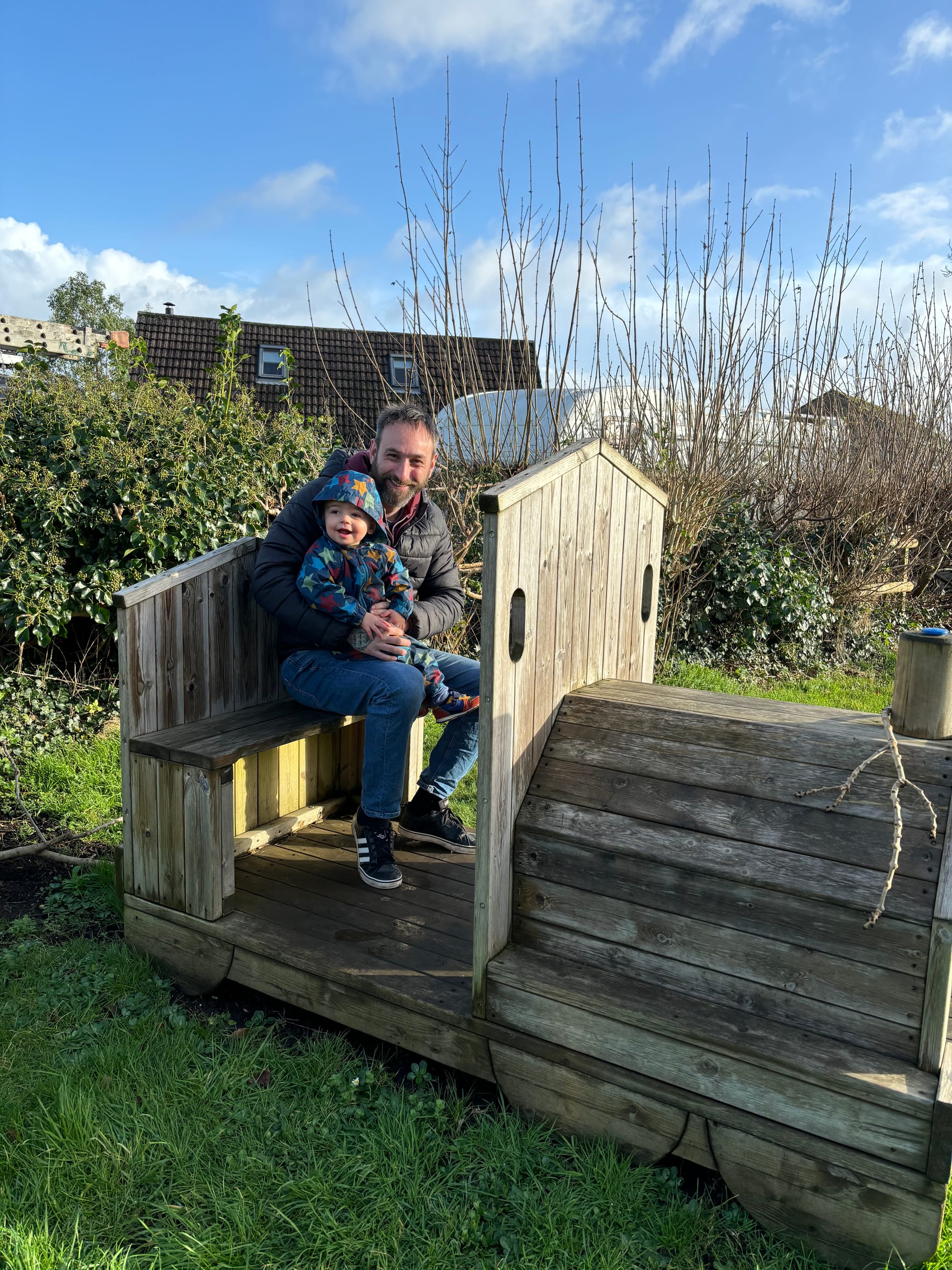 Mark sitting on a wooden train with baby William