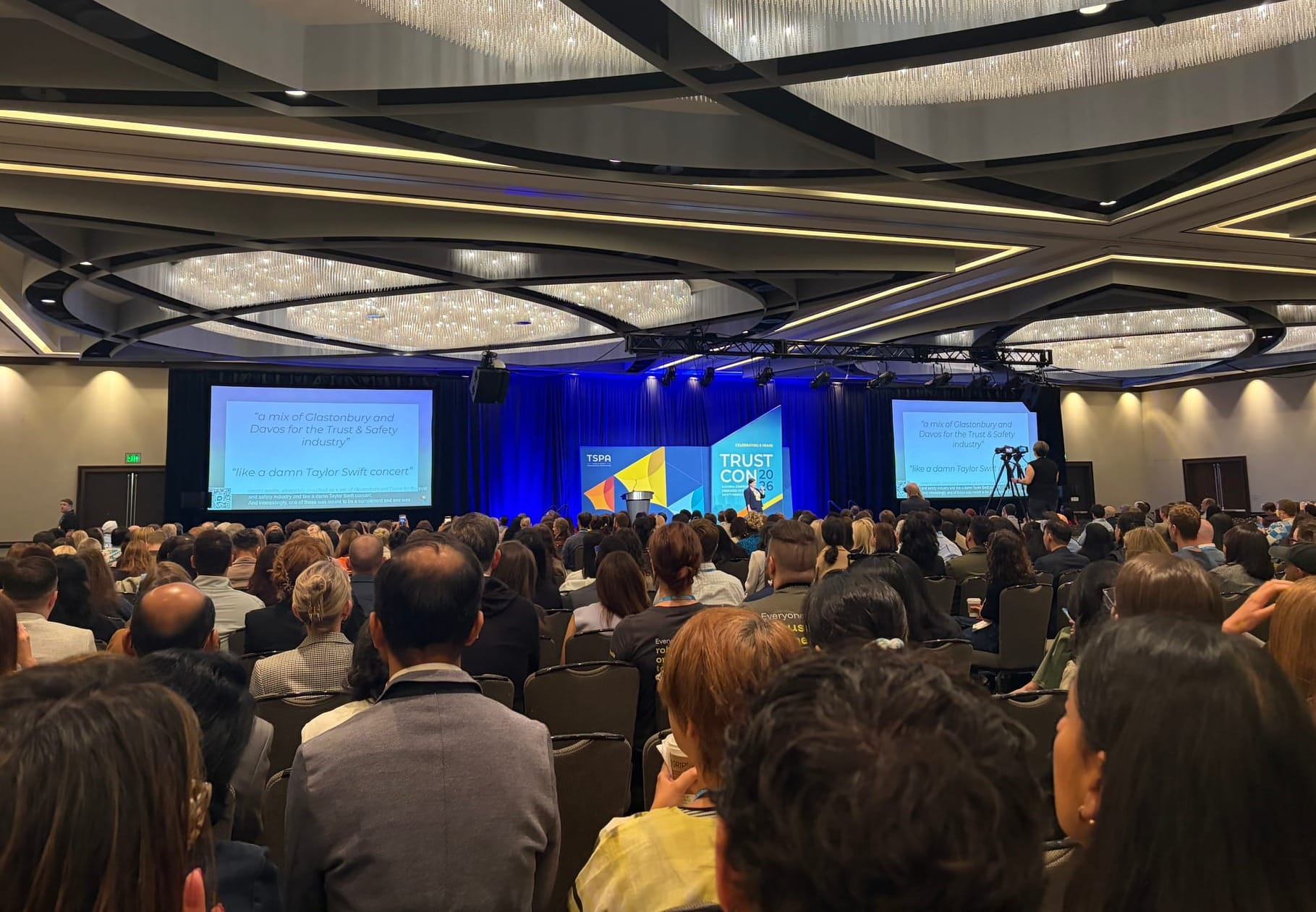 A woman standing up at TrustCon giving a presentation in front of a crowd