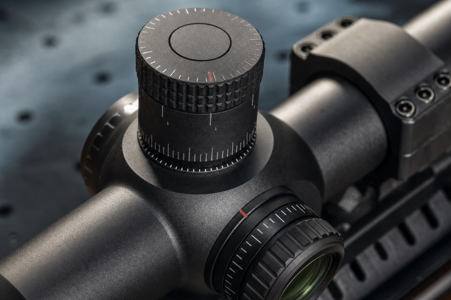 A close detail of an unbranded high-magnification scope turret and top parallax control under range light.