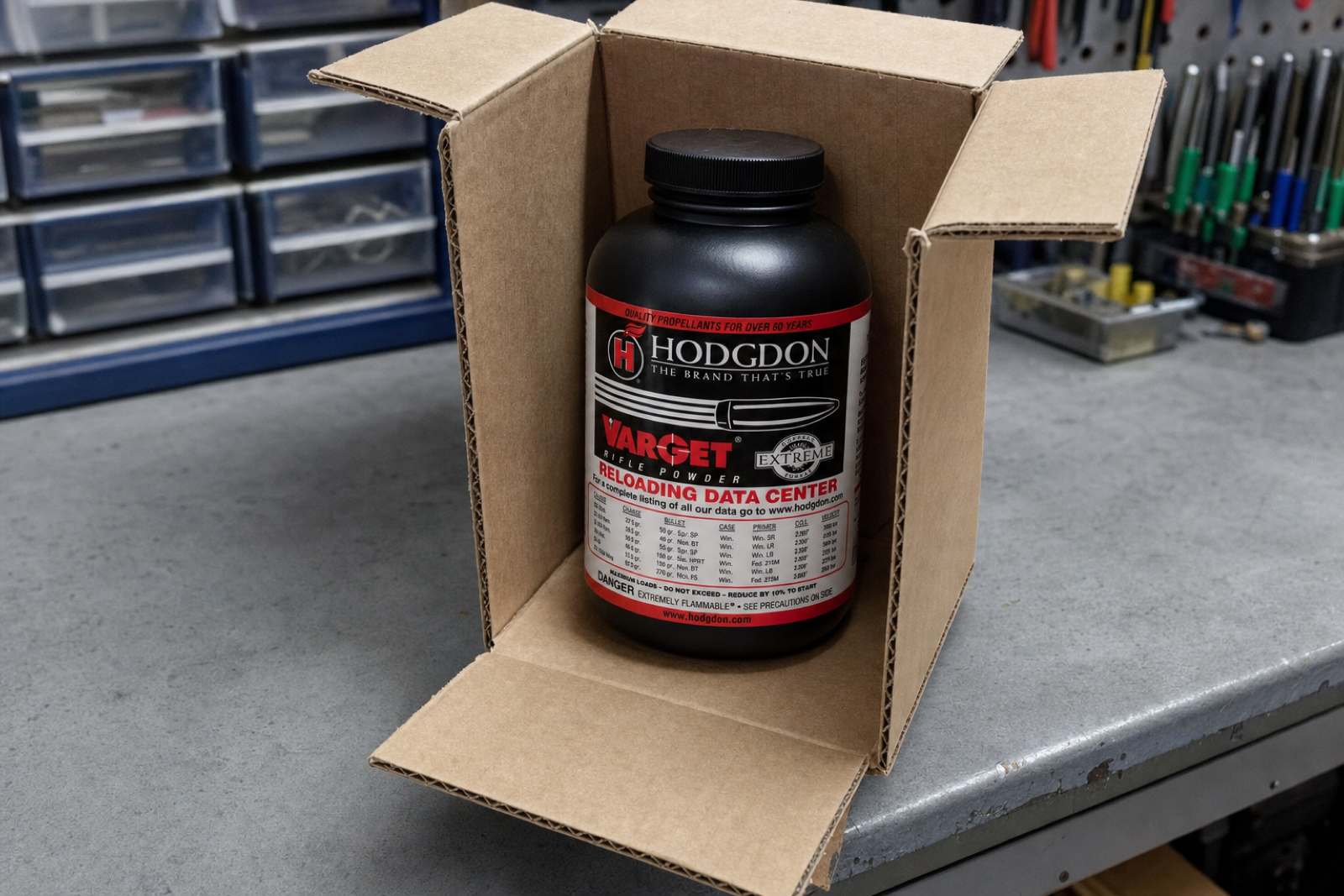 A capped powder bottle with its original label stands inside an open corrugated carton on a grey bench.