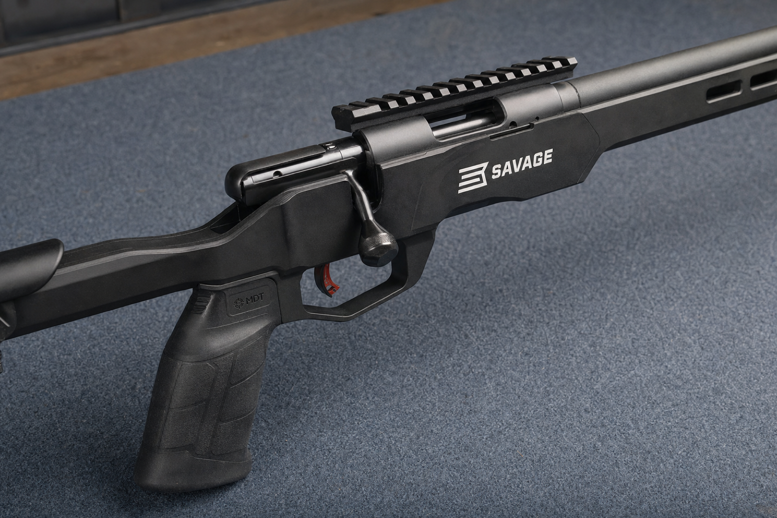 Close right-side view of a Savage B22 Precision receiver, closed bolt handle, and connected black chassis on a work mat.