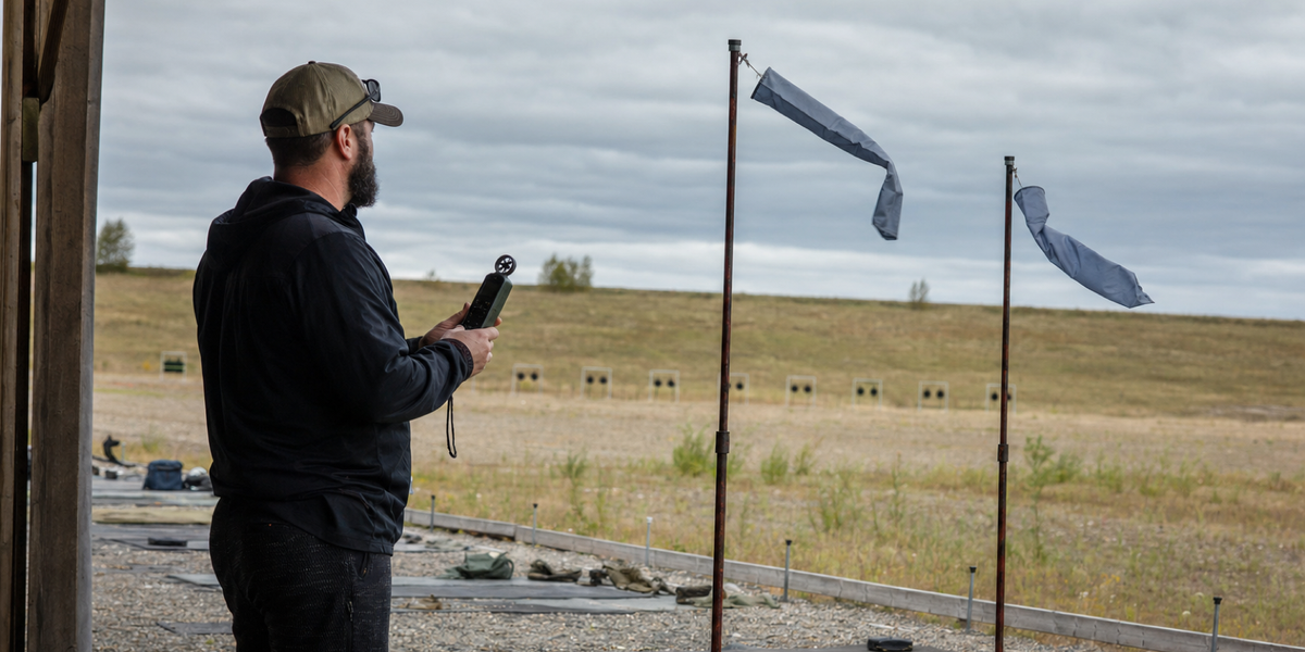 A fictional range coach watches two wind flags at an unnamed Canadian long-range firing point.