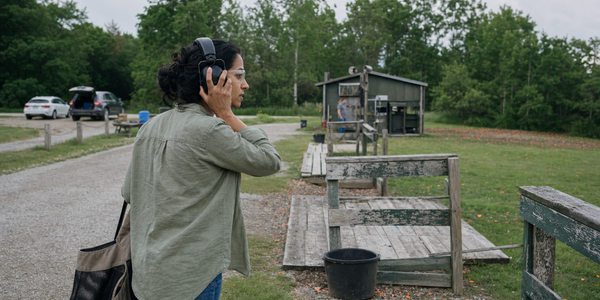 An adult newcomer adjusts her hearing protection as she steps onto a southern Ontario clay-target field.