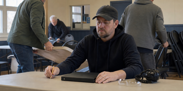 An adult pauses over a closed binder during a Canadian licensing-course break.