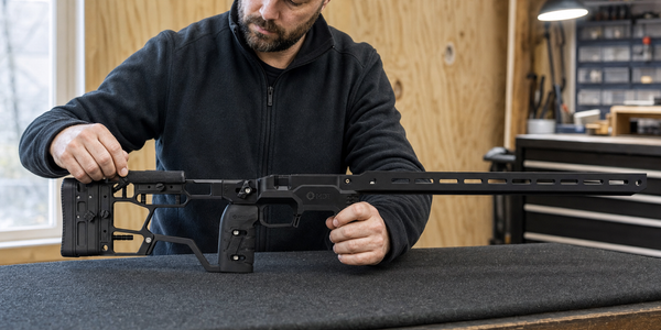 An owner adjusts a bare MDT ACC Elite chassis on a padded workbench.