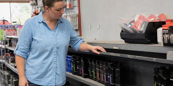 Generated photograph of a fictional component-shop worker checking a partly filled retail shelf.