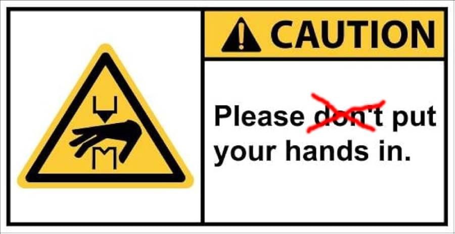 A Caution Sign. On the left, an icon of a hand being caught in machinery. On the right, text reading: "CAUTION Please don't put your hands in." "Don't" has been crossed out with red pen.