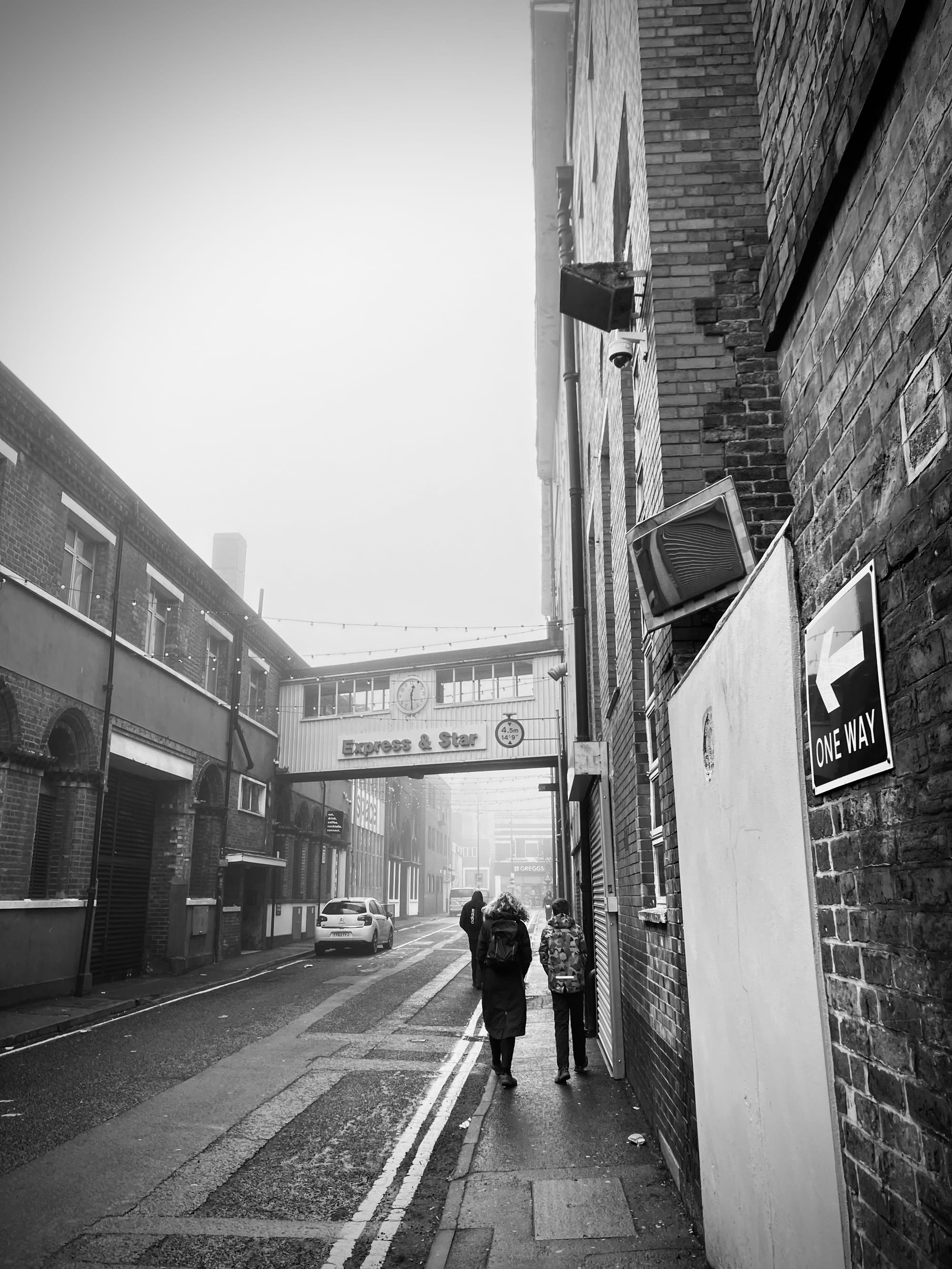 A black and white photo of people walking past a building with an Express and Star sign on it.