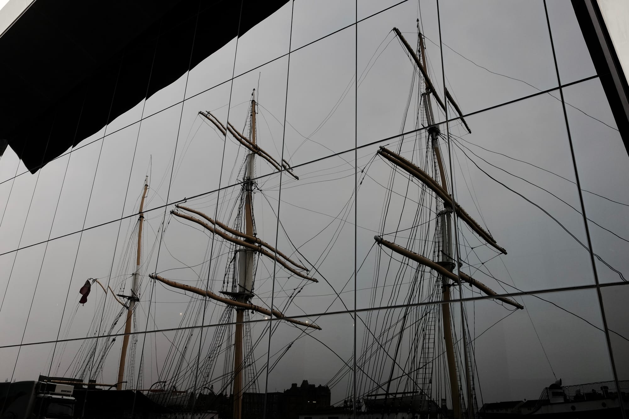 The masts of a tall ship are reflected in the glass of the Riverside Museum, Glasgow
