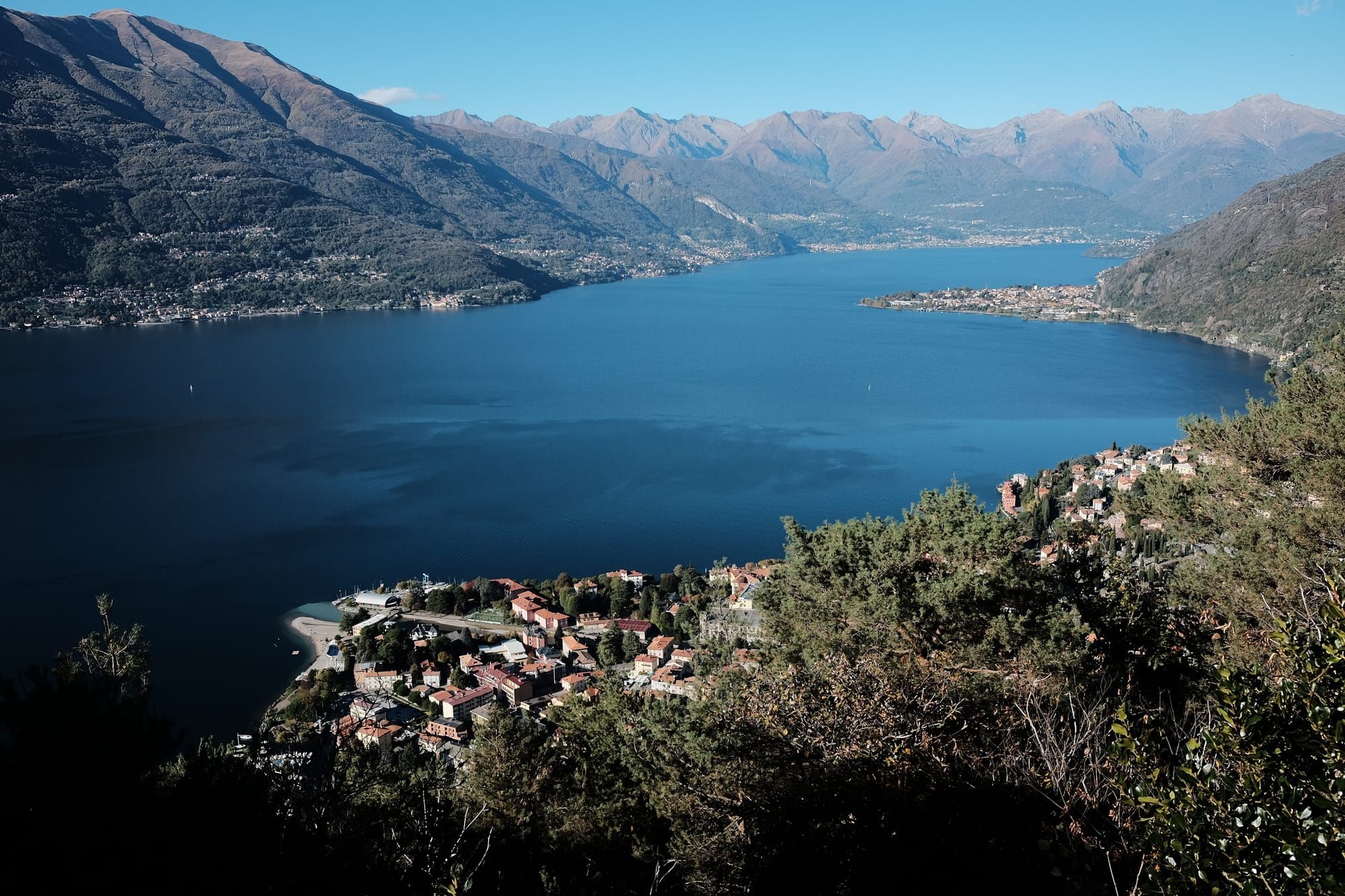 A view of Bellano on the shores of Lake Como – red-roofed buildings surrounded by wooded hillside.