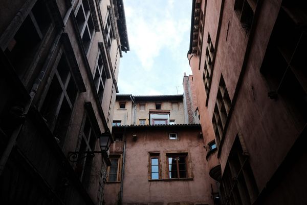A courtyard in Lyon surrounded by buildings with terracotta-coloured render.