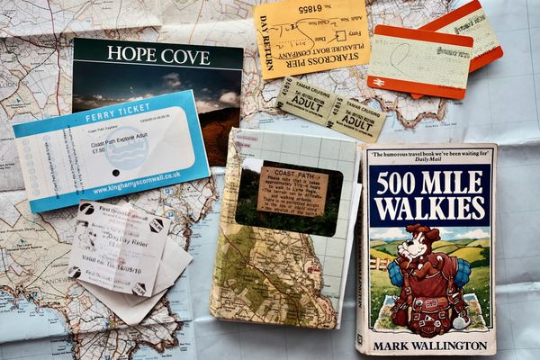A collection of books, ferry tickets, train tickets and other memorabilia lie on a map of Cornwall.