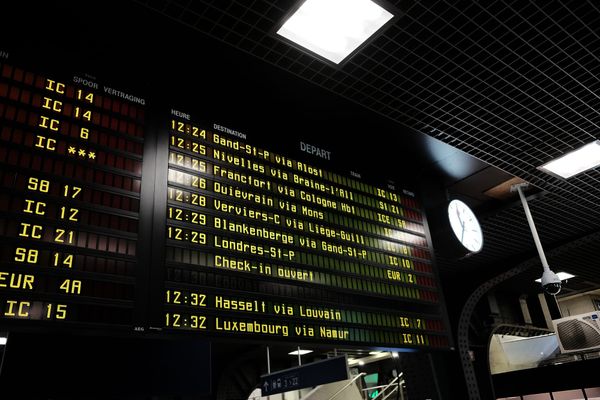 A departures board at Brussels Midi station lists train times and destinations in bright yellow writing
