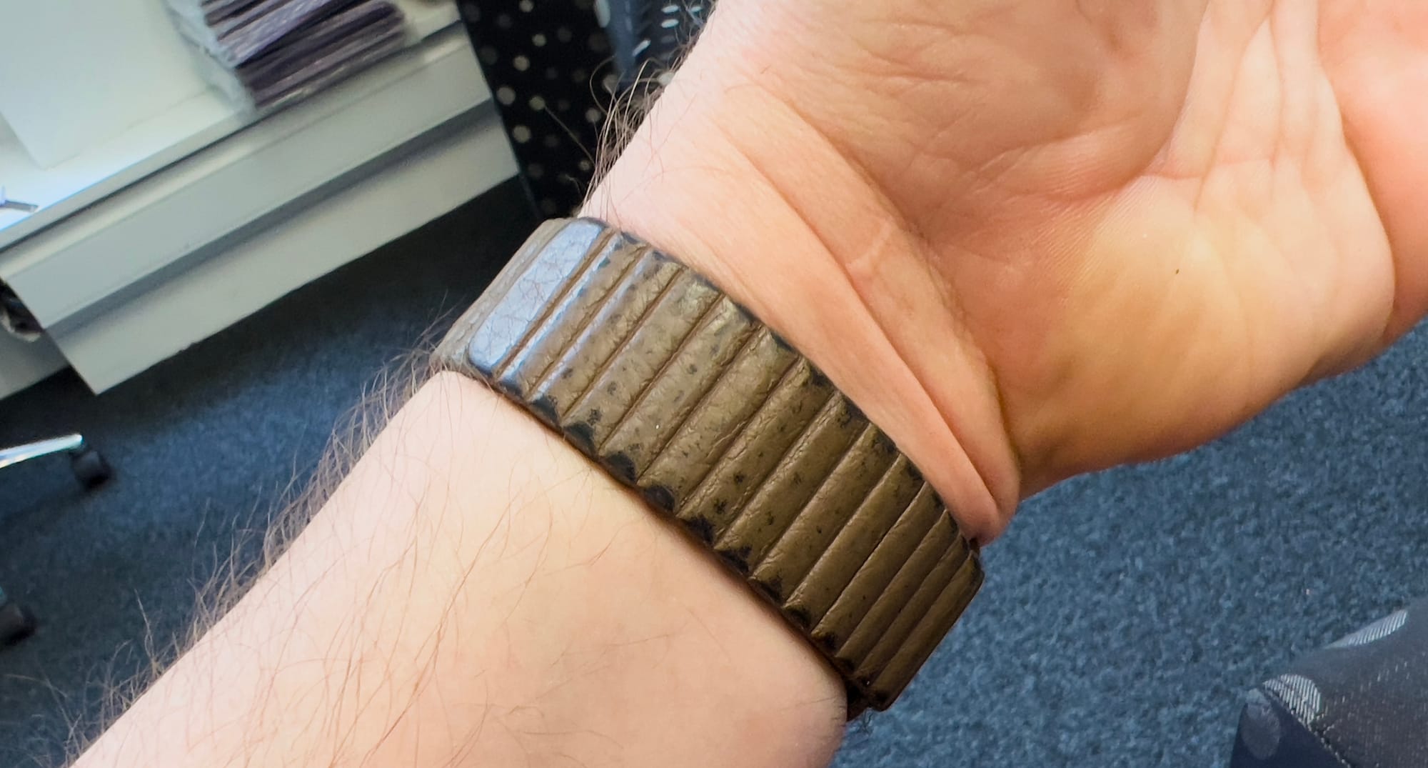 A leather Apple Watch strap showing a worn patina. 