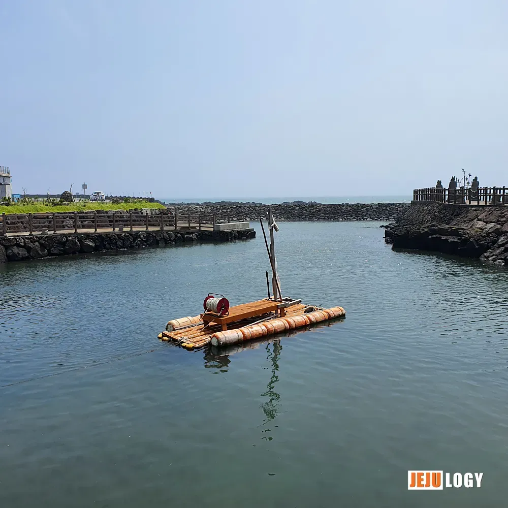 [4] A traditional Jeju teu raft sits on the calm water inside the port — a quiet nod to how people once worked these shores. — webp_20200804_112449.webp