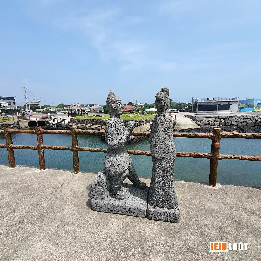 [7] Stone figures stand quietly along the walkway — likely a nod to the founding myth that gives this village its meaning. — webp_20200804_112627.webp