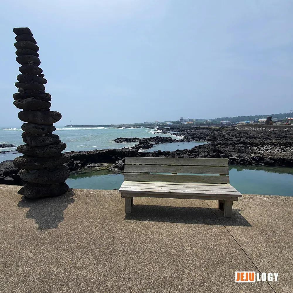 [8] A bench and a small cluster of stone cairns near the port — a place that invites you to sit and slow down. — webp_20200804_113342.webp