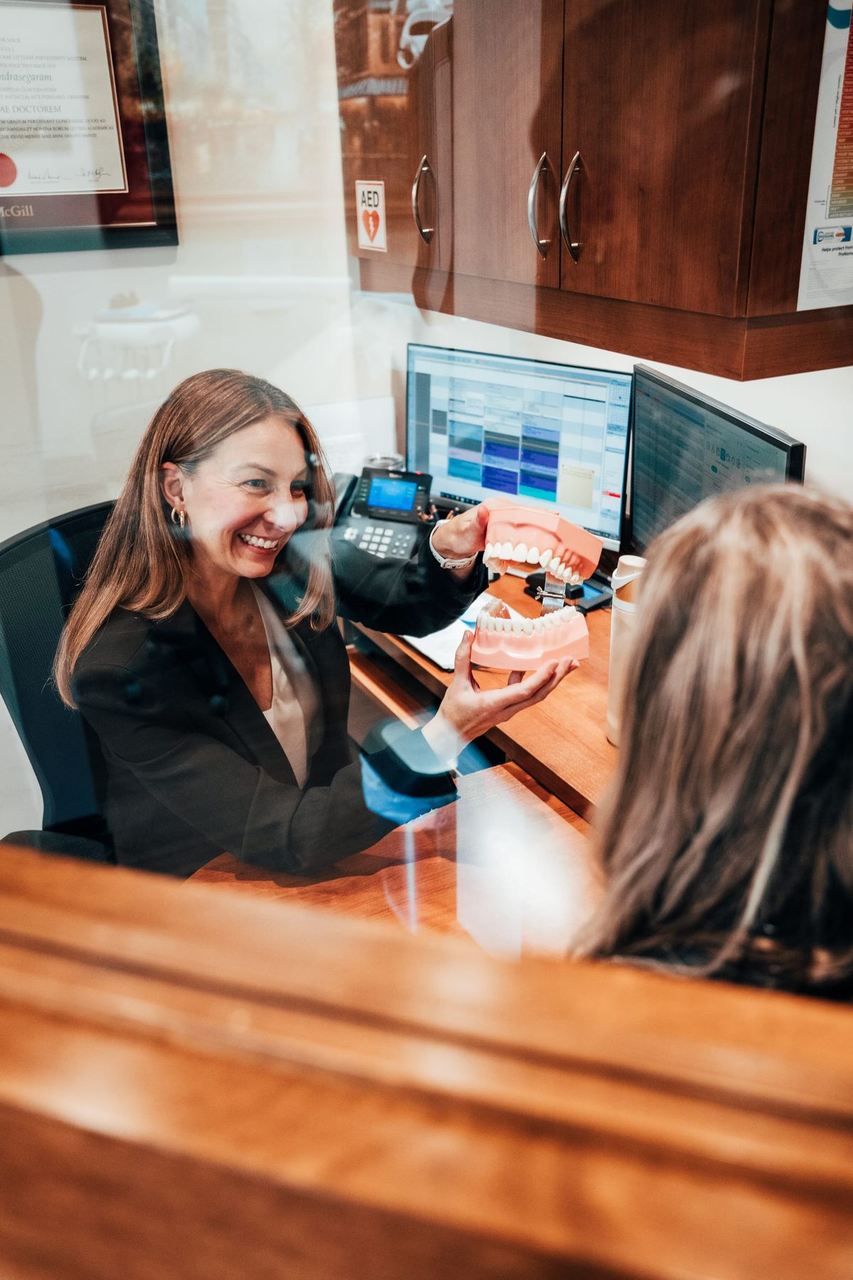 Laura sitting in the treatment coordination room with a patient, holding up a model of teeth