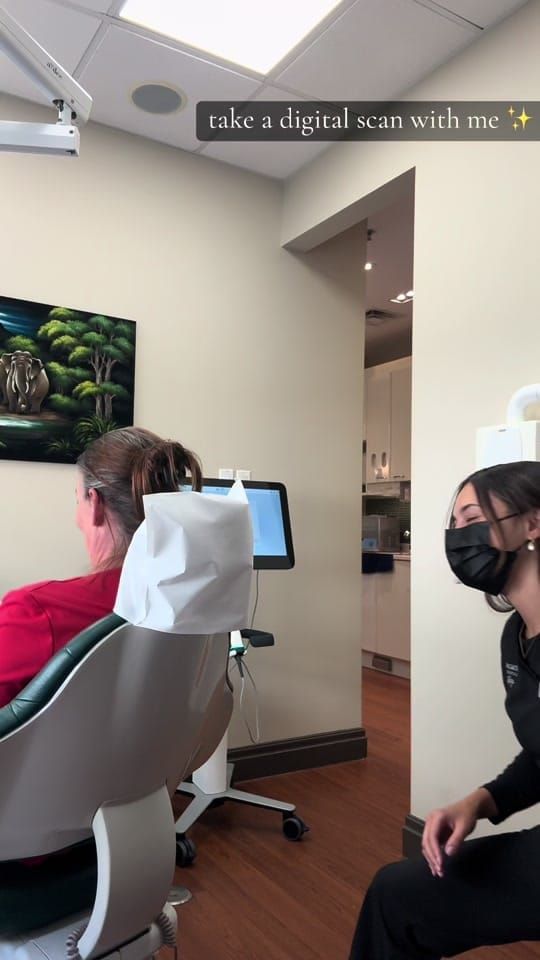 A patient reclines while a masked assistant runs an iTero digital scanner beside the screen at Longworth Dental Bowmanville.