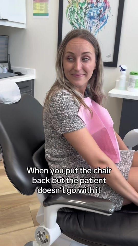 A patient sitting upright in the dental chair with a wry look at Longworth Dental Courtice, with on-screen text reading: when you put the chair back but the patient doesn't go with it.