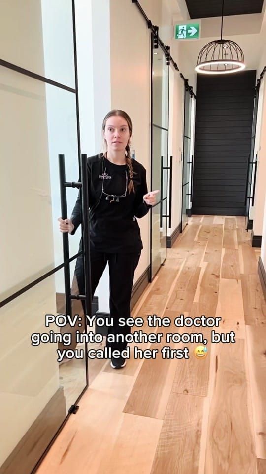 Dr. Sharon Barr with loupes in a hallway at Longworth Dental Courtice, holding a glass door.