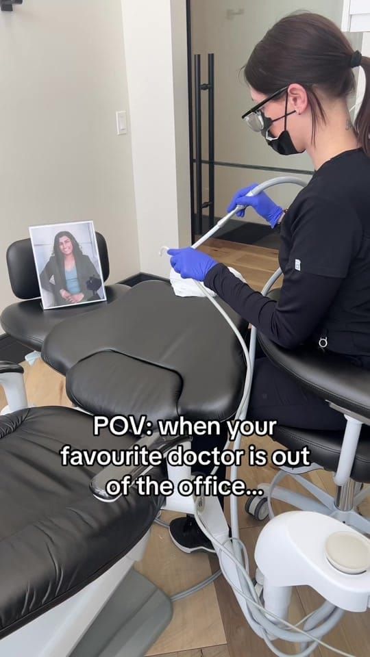 A masked Longworth Dental assistant works at a treatment chair beside a framed photo of the dentist who is out of the office.
