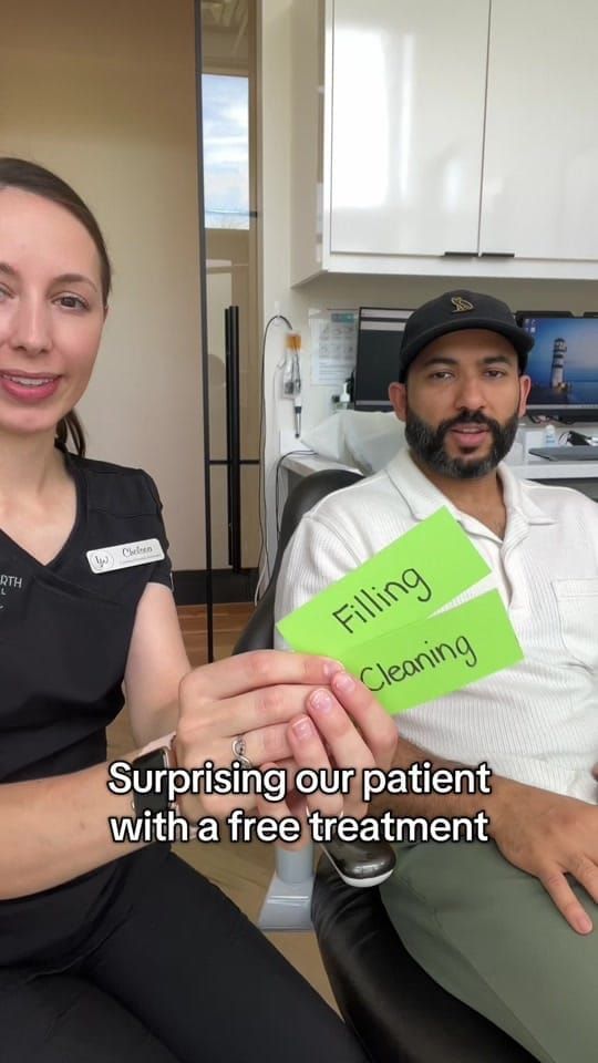 Chelsea holding 'Filling' and 'Cleaning' cards beside a smiling patient in the chair at Longworth Dental Courtice.