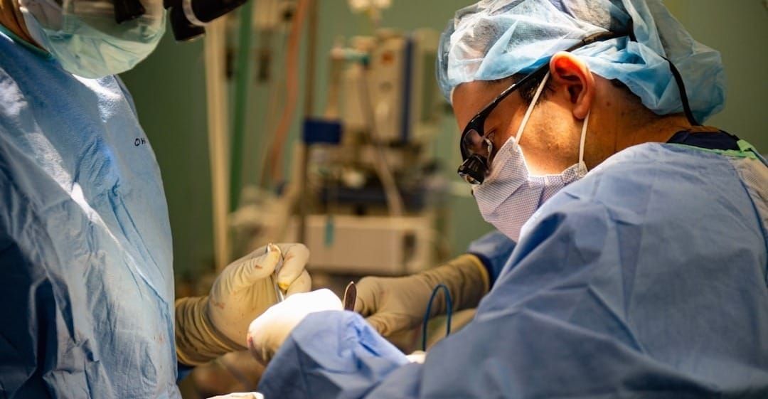 Surgeons in sterile gowns performing a medical operation.