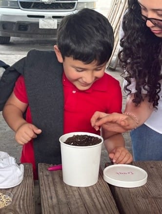 A child looking at a plant in a pot

AI-generated content may be incorrect.