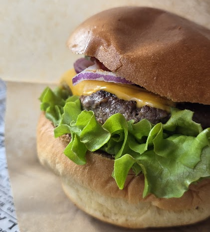 Gros plan sur un burger au fromage, à l'oignon et à la salade chez Green Van.