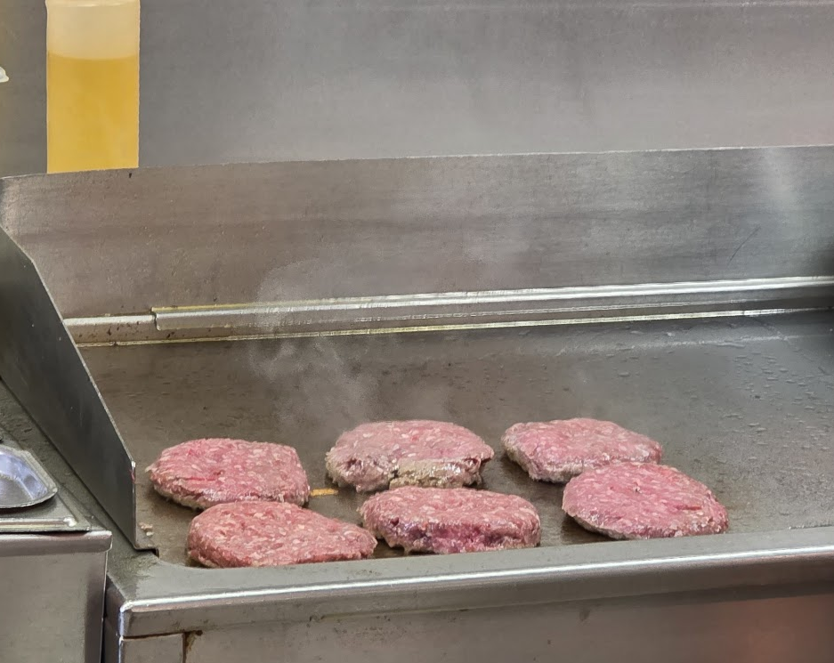 Plaque de cuisson avec des steaks hachés en train de griller chez Green Van au Flon