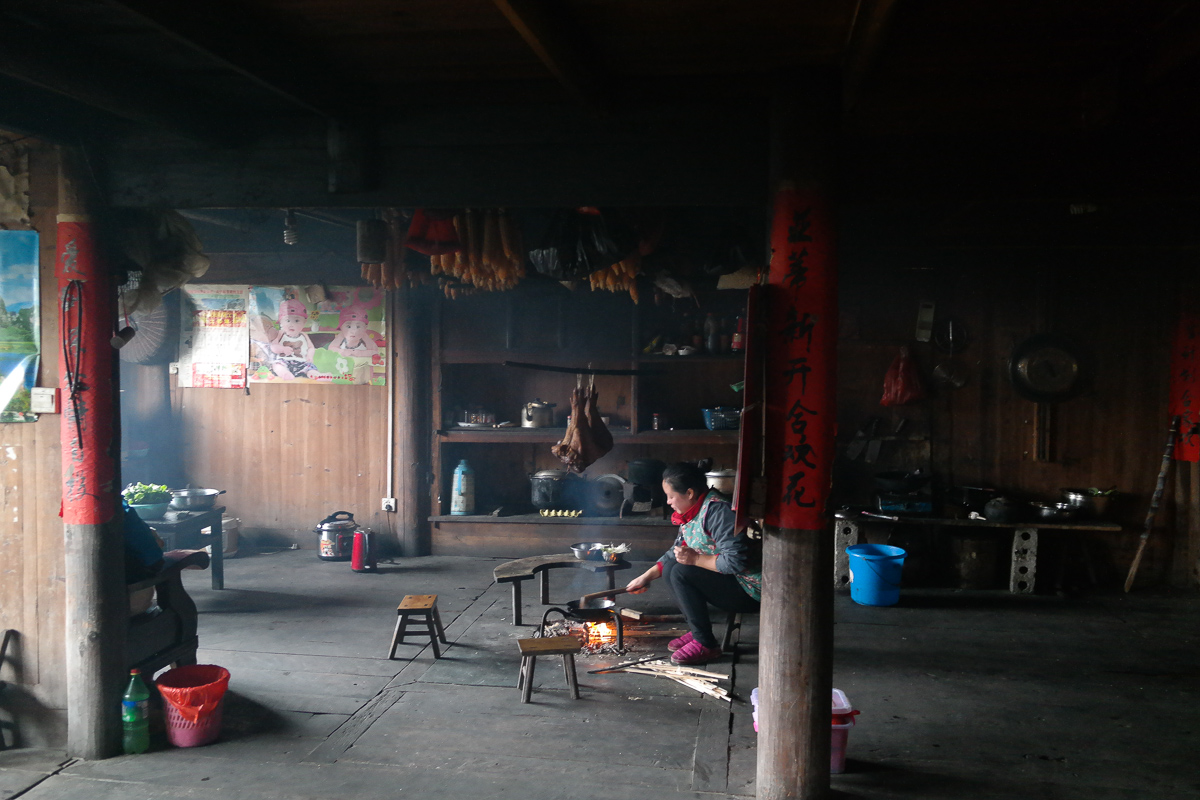 Une femme qui cuisine sur une flamme directe avec un wok dans un village chinois.