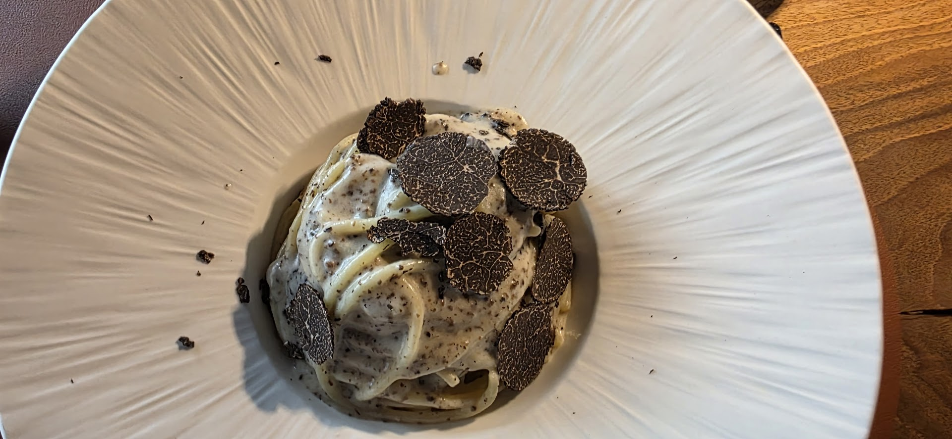 Des spaghettoni avec des tranches de truffes noires vues du dessus.