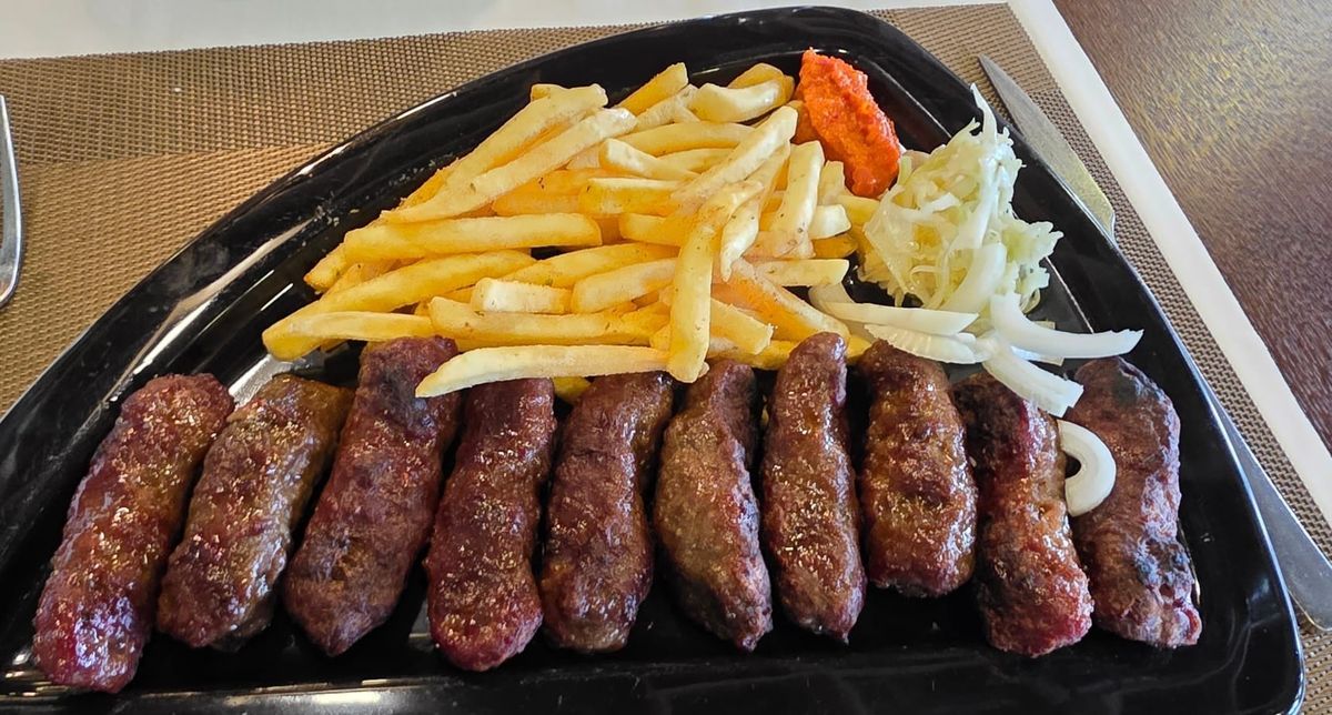 Une assiette avec 10 cevapcici, des frites et des légumes 
