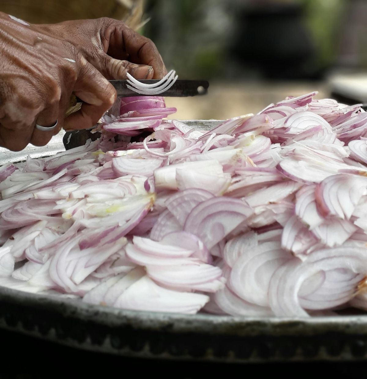 Photos d'oignons en grande quantité en train d'être coupés. 