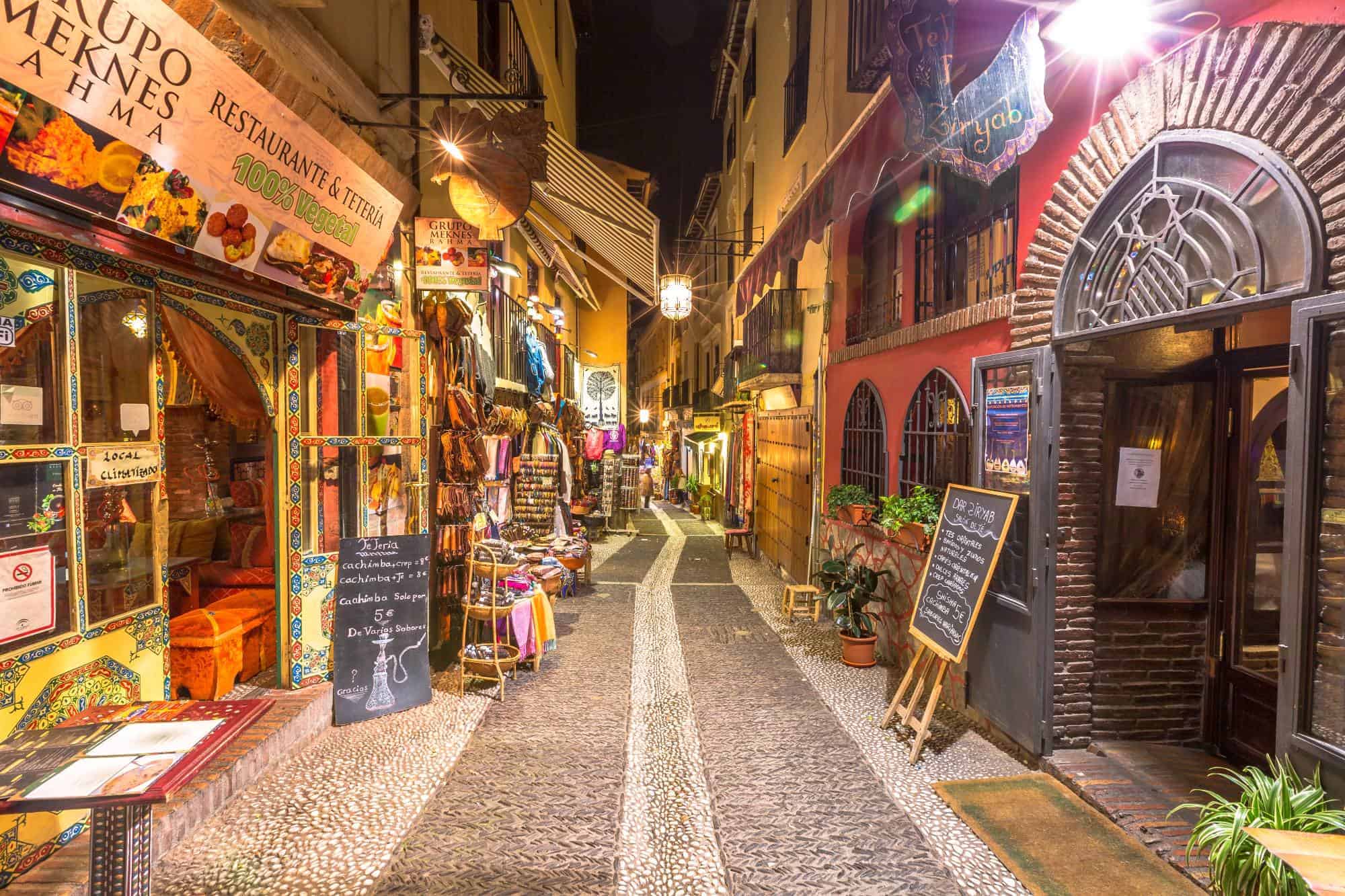 Granada's restaurants and shops in a street of the popular old Moorish quarter Albaicin illuminated at night. 