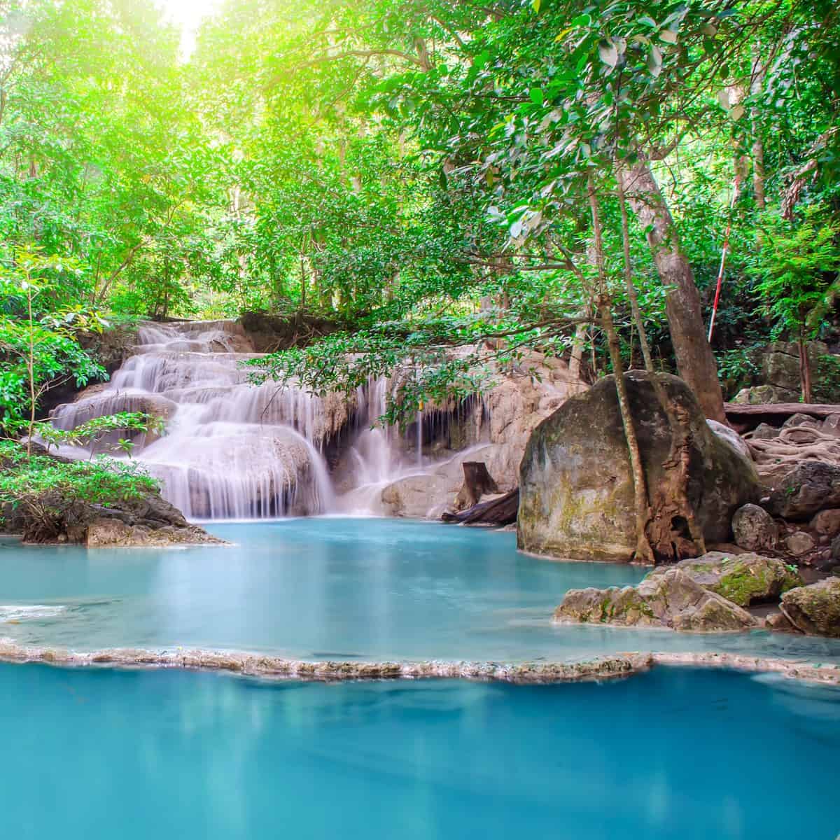 beautiful waterfall with sunlight rays in deep forest,