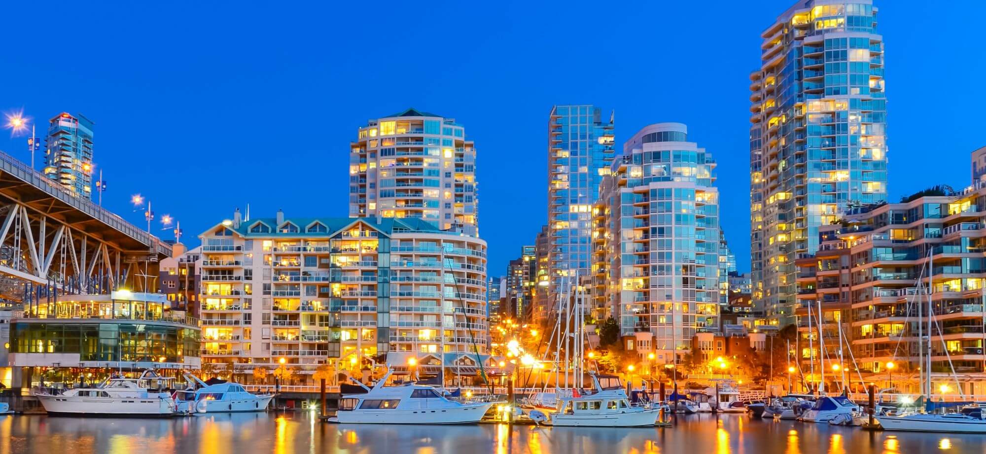 Panoramic skyscrapers reflection along False Creek riverside in Vancouver BC at blue hour

