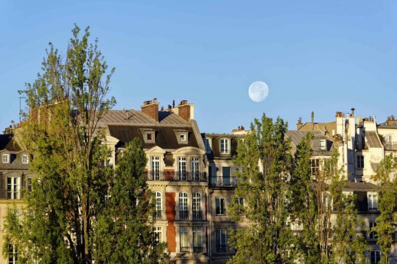 Daytime full moon rises over Paris residences