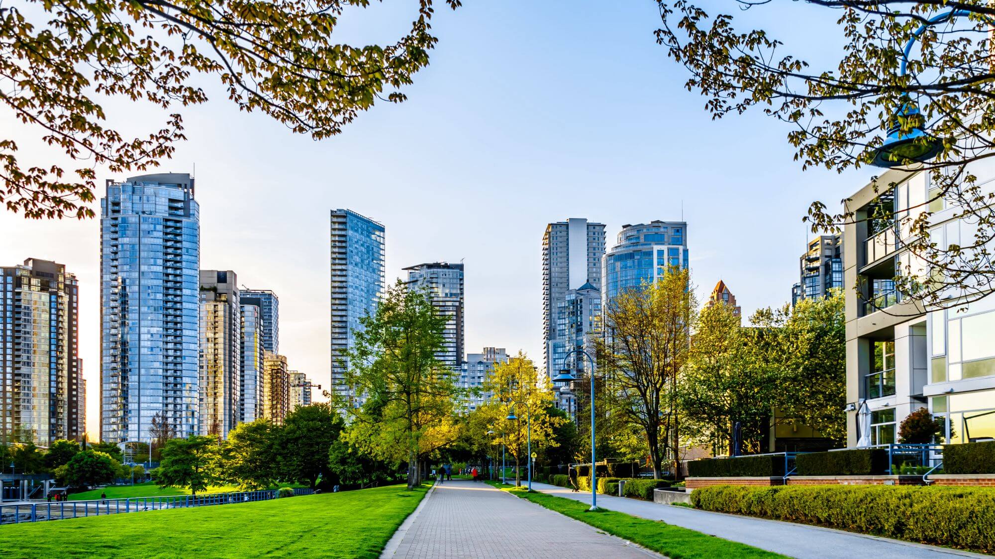 A city park with apartment buildings around - a paved path among green lawns
