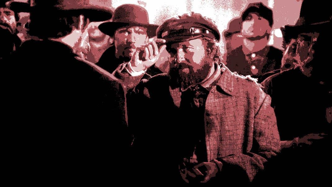 Man tips his hat to another man within an angry crowd