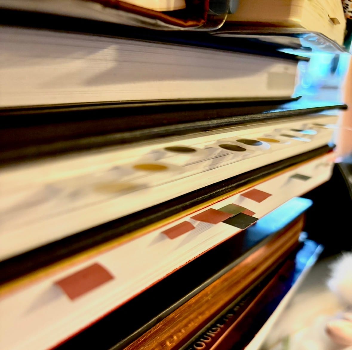 Picture of books stacked on each other with book tabs in them.