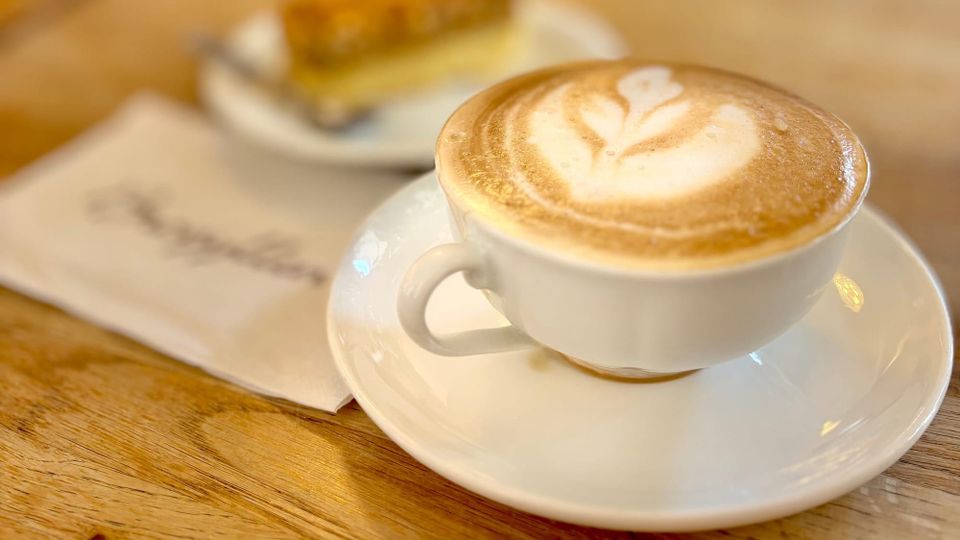 A photo of a white coffee cup with a cappuccino.