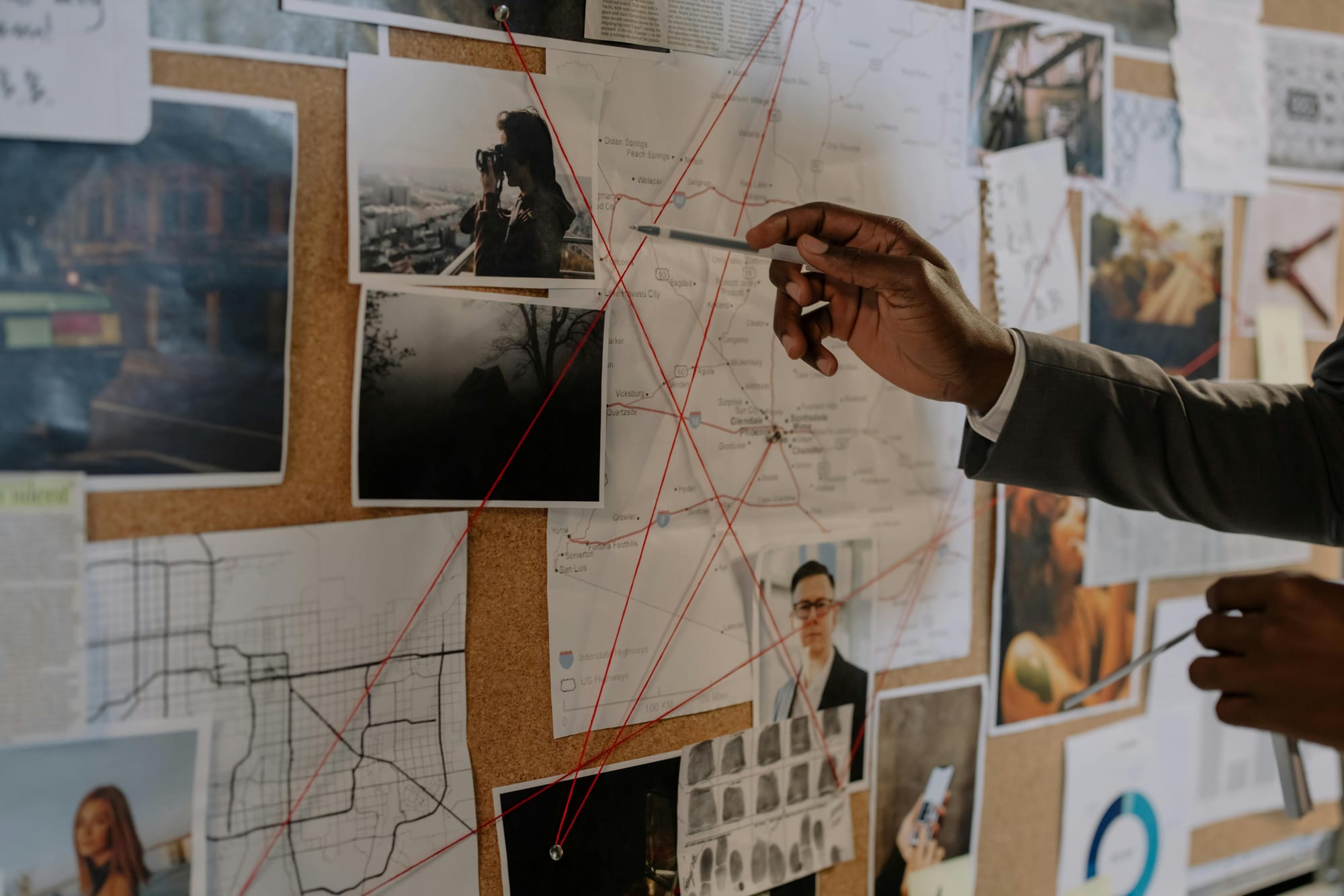 Tablero de estrategia con mapas, fotografías y líneas conectadas, mientras una persona señala información clave como parte del análisis y planificación de una campaña política.
