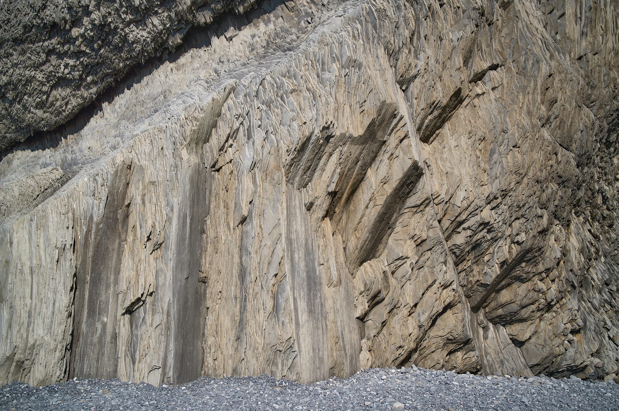 Tan and white rock face with vertical and 45 degree angled veins.